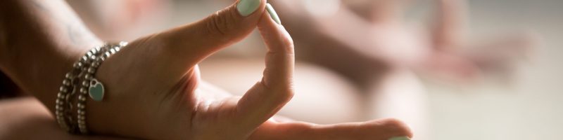 Gyan mudra close up, woman joining together the tip of index finger with thumb, wearing wrist bracelets, practicing yoga in concentration pose, stress relieve exercise at home, focus on right hand